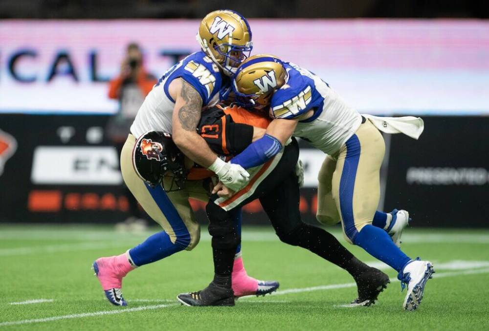 DARRLY DYCK / THE CANADIAN PRESS FILES
Blue Bombers defensive tackles Casey Sayles (left) and Adam Bighill take down B.C. Lions QB Michael Reilly last season in Vancouver. After bouncing around between the NFL, AAF and XFL, Sayles has finally found some stability in Winnipeg.