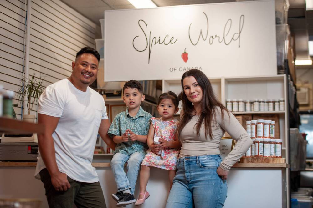 ETHAN CAIRNS / WINNIPEG FREE PRESS
Aaron Delos Santos and his wife Madilyn with their children Jude and Emme stand in front of their counter in their business Spice World.