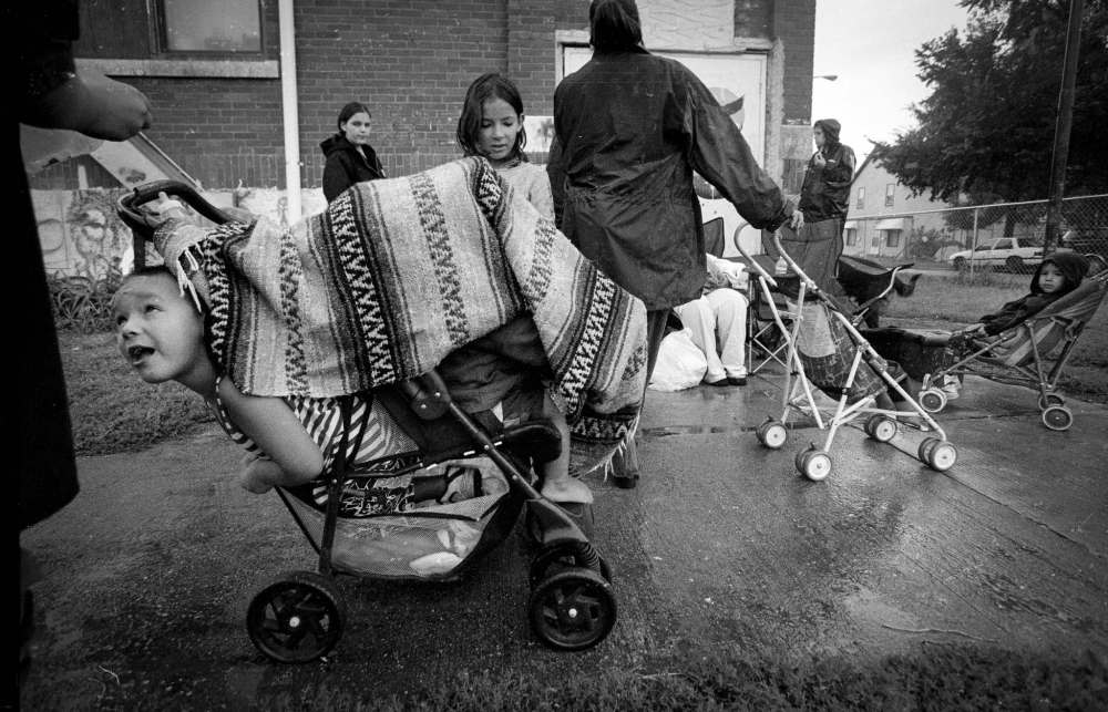 AUGUST 2001: Margaret's son Jason, 5, pokes his head out from underneath a blanket covering his sibling's stroller outside a North End prenatal clinic.