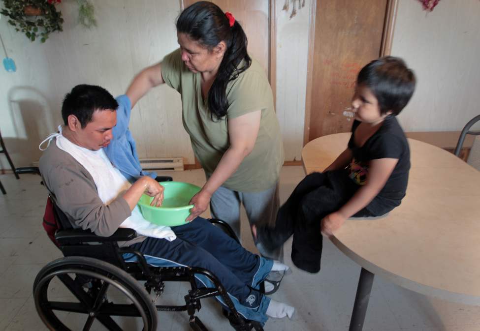JOE.BRYKSA@FREEPRESS.MB.CA
Eugene Taylor, 27, who has cerebral palsy, is cleaned by his mother Helen in their Garden Hill home. They get water delivered in limited quantities, but find it tough because of the high volume required to look after a son with a disability.