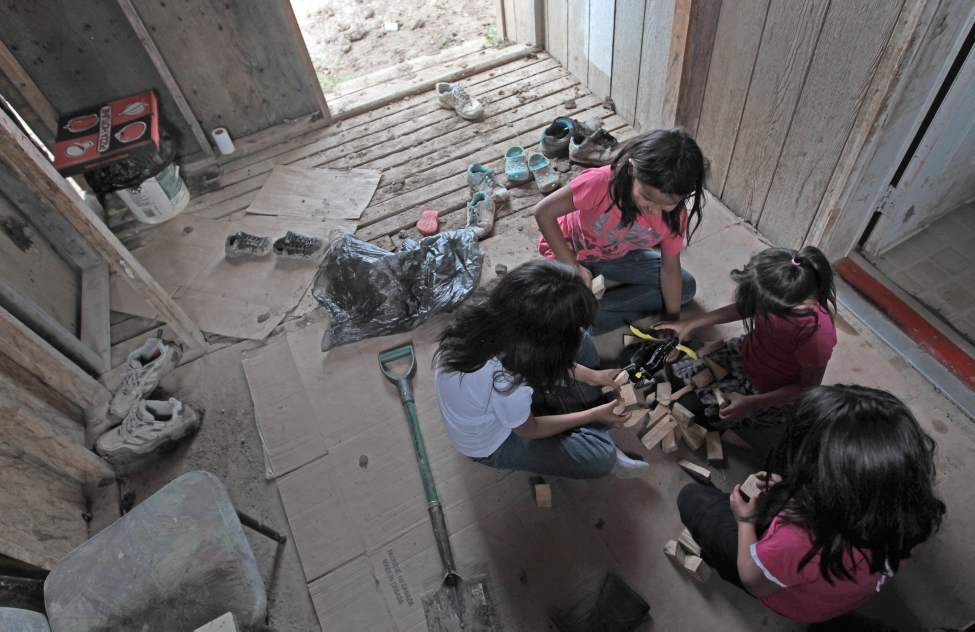 JOE.BRYKSA@FREEPRESS.MB.CA
Kids play in a porch near a slop pail used as a toilet, in one of many homes in the area with no running water.