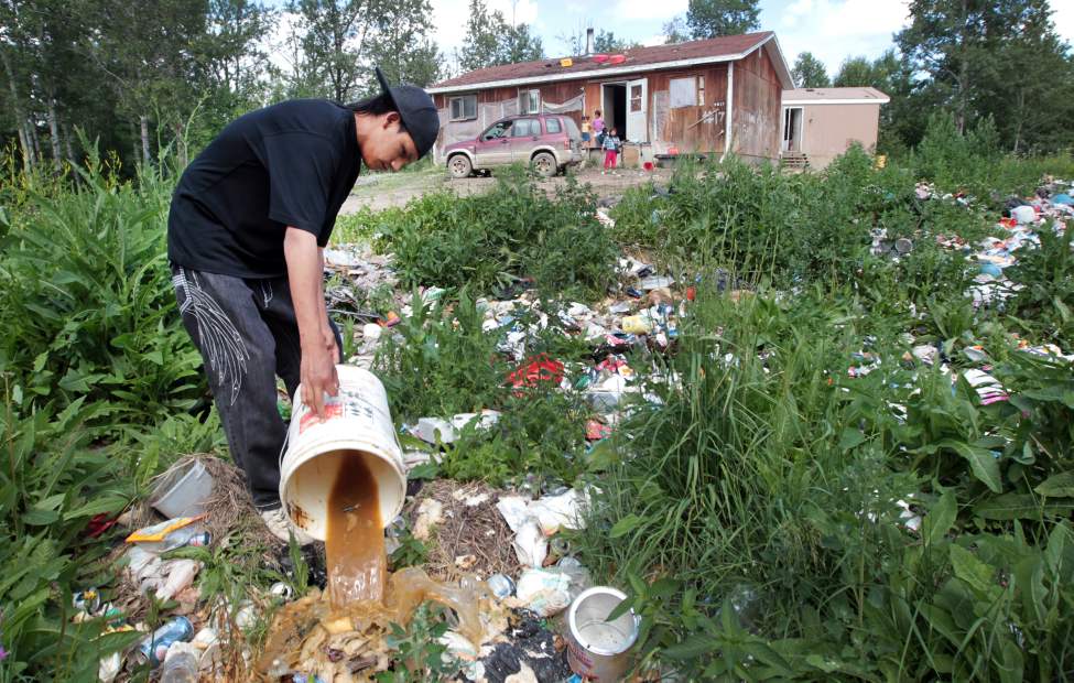 JOE BRYKSA/WINNIPEG FREE PRESS
Solomon McPherson dumps a slop pail full of sewage into a makeshift dump just outside his home. Sewage on the ground could infect children playing in the area or run into the lake, where some people still get their drinking water.