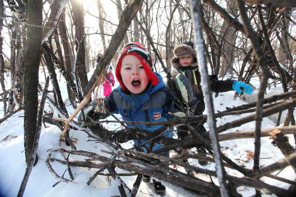 Ruth Bonneville / Winnipeg Free Press
Owen Edmonds, 5, growls as he pretends to be a bear while playing with Jessie Reid, 5, and his sister, Alice Edmonds, 3, in a pretend cage made of sticks in the woods at Assiniboine Park Saturday morning. The structures were made by children and childcare workers in an early childhood education program as part of a initiative to get kids playing outside creating things with nature.