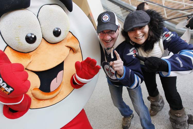 John Woods / The Canadian Press
Allen Hurton and Bessie Hatzitrifonos celebrate with Peter Puck prior to NHL action between the Ottawa Senators and Winnipeg Jets in Winnipeg