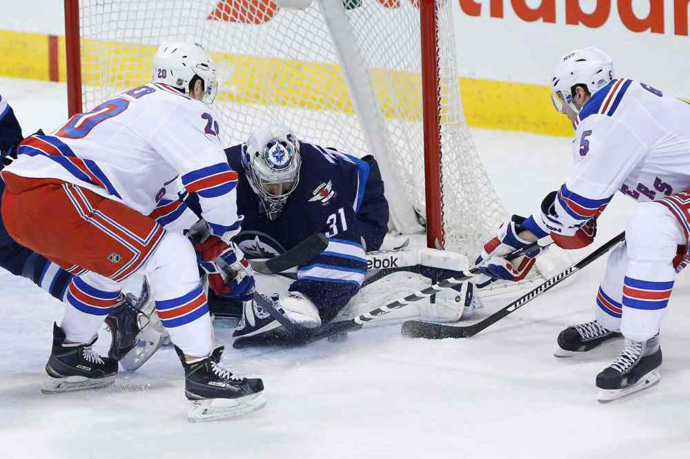 JOhn Woods / The Canadian Press
Winnipeg Jets goaltender Ondrej Pavelec (31) jumps on a loose puck as New York Rangers' Chris Kreider (20) and Dan Girardi (5) look for the rebound during first period at the MTS Centre Tuesday.