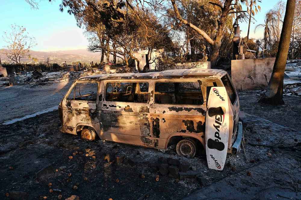 A burned surfboard and a van are all that remain in the front of a destroyed home in the Point Dome neighborhood in Malibu, Calif., Monday. (Richard Vogel / The Associated Press)