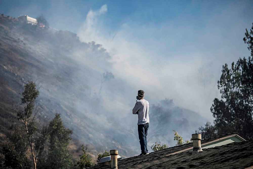Residents watch from their roofs as firefighters stop the forward progress of the Peak Fire in Simi Valley, Calif. Monday. (Marcus Yam / Los Angeles Times)