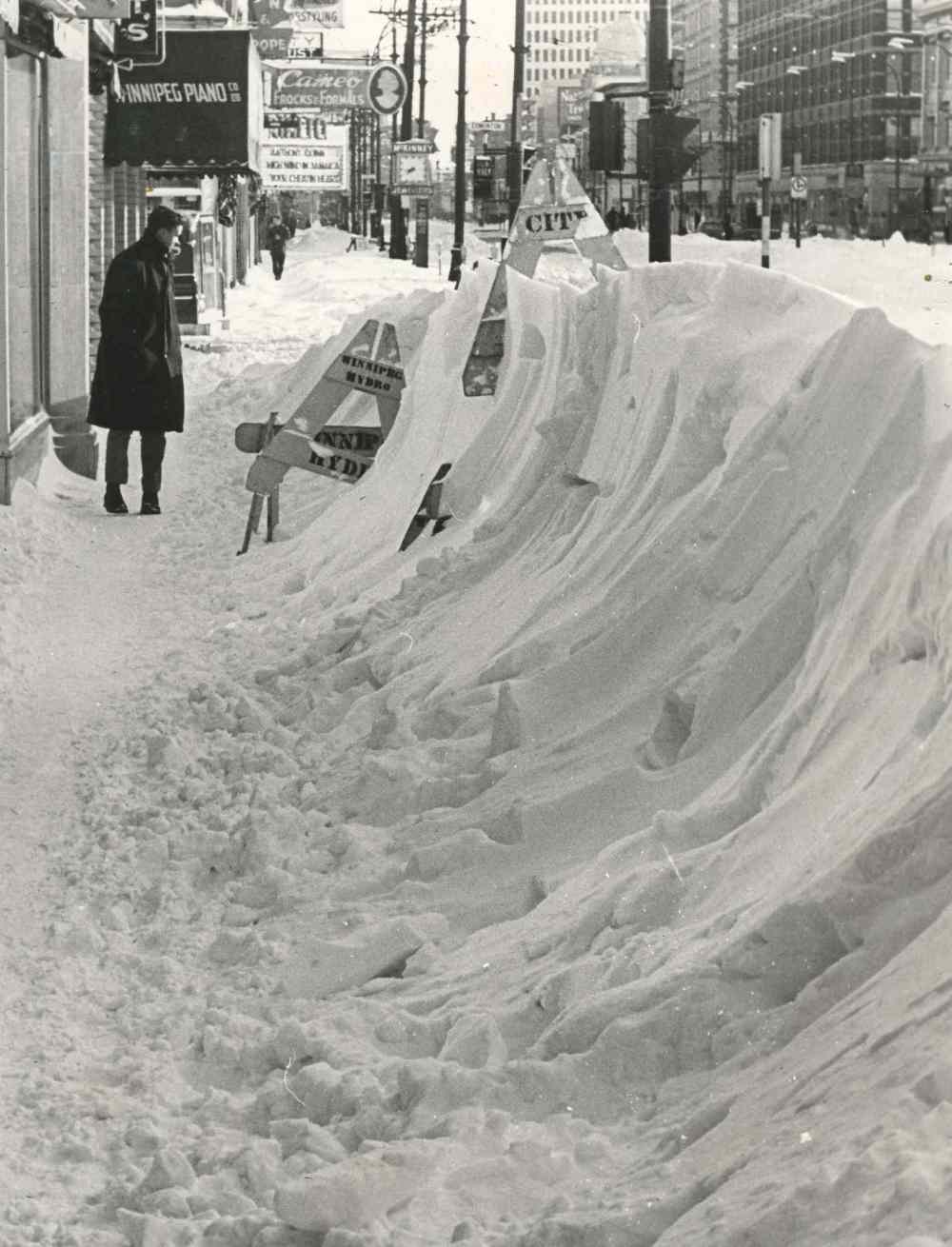 Surveying the results of the blizzard was part of the game for pedestrians along Portage Avenue who gaped in wonderment at snow hurled high along the sidewalks. (Winnipeg Free Press Archives)