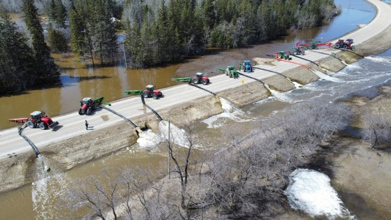 This photo taken by a drone shows tractors pumping floodwater over Highway 68 about a kilometre west of Arborg on May 4. (North-East Interlake Emergency Measures Board)