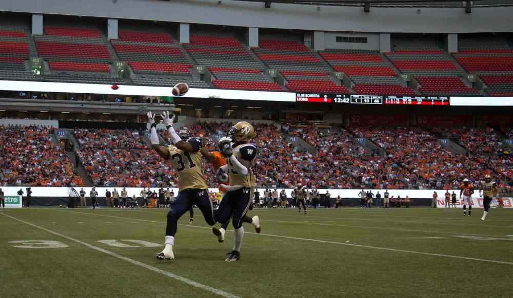 DARRYL DYCK / THE CANADIAN PRESS
Winnipeg Blue Bombers' Maurice Leggett (31) intercepts a pass intended for B.C. Lions' Shawn Gore, back, as teammate Bruce Johnson watches during the first half of Friday's game.