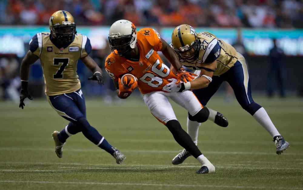 DARRYL DYCK / THE CANADIAN PRESS
B.C. Lions' Courtney Taylor, centre, is grabbed by Winnipeg Blue Bombers' Teague Sherman, right, as Demond Washington, left, trails the play during the first half of Friday's game.