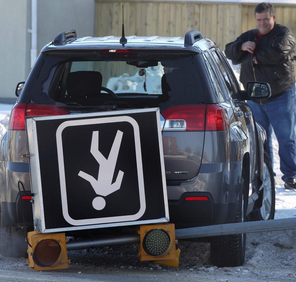 Winter Driving - A man looks at his vehicle on Regent Ave West and Moroz Street. No one was injured, but a large pedestrian corridor sign was knocked to the ground in the mishap. January 16, 2013 (JOE BRYKSA / WINNIPEG FREE PRESS)