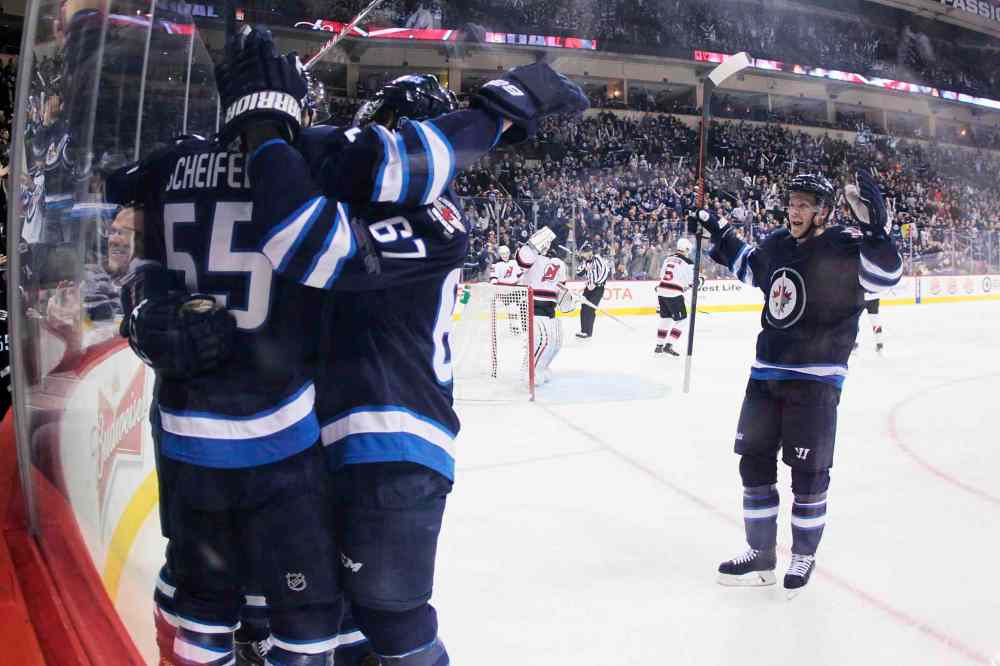 John Woods / The Canadian Press
Winnipeg Jets' Mark Scheifele (55), Michael Frolik (67) and Toby Enstrom (39) celebrate Scheifele's goal against the New Jersey Devils during the second period.