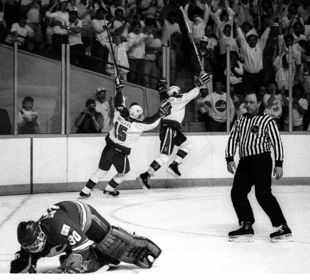 Hawerchuk and Paul MacLean celebrate a goal on Calgary's Mike Vernon as a crowd dressed in white goes wild at a playoff game on April 16, 1987. (Wayne Glowacki / Winnipeg Free Press files)