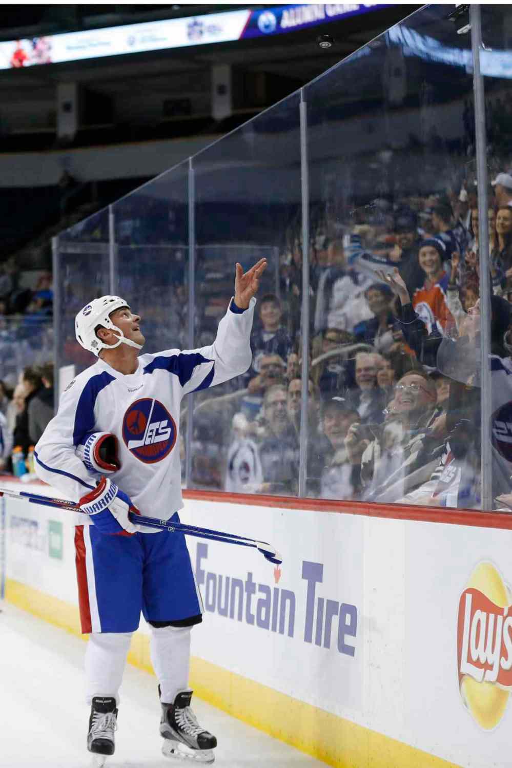 Hawerchuk tosses a puck to the crowd during the practice for the NHL's Heritage Classic Alumni Game. (John Woods / The Canadian Press files)