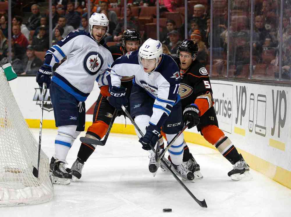Jae C. Hong / The Associated Press
Winnipeg Jets' Adam Lowry, centre, moves the puck past Anaheim Ducks' Korbinian Holzer, right, and Shea Theodore as teammate Alexander Burmistrov, left, watches during the first period of Sunday's NHL hockey game in Anaheim, Calif.
