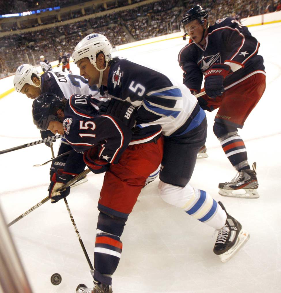 Jets #5 Mark Stuart fights for possession in the corner against Columbus' #15 Derek Dorsett in the Jets' first home game in 15 years. (Phil Hossack / Winnipeg Free Press)