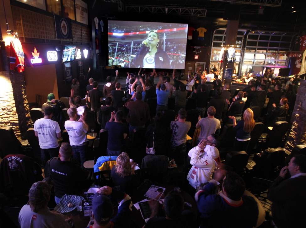 Winnipeg Jets fans in the 4Play Sports Bar cheer as the Canadian anthem is song across the street in the MTS Centre Tuesday at the start of the exhibition game between the Winnipeg Jets and the Columbus Blue Jackets. (WAYNE GLOWACKI/WINNIPEG FREE PRESS)