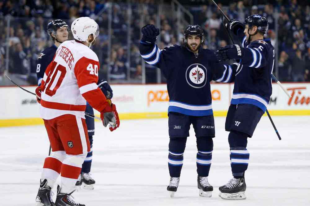 John Woods / The Canadian Press
Winnipeg Jets' Mathieu Perreault (85) and Mark Stuart (5) celebrate Perreault's second-period goal as Detroit Red Wings' Henrik Zetterberg (40) skates by.