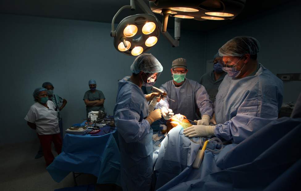 Surgeon Eric Bohm (left), Dr Jon March (centre) and Dr Jason Crosby work on replacing a knee while Nicaraguan surgical nurses watch.