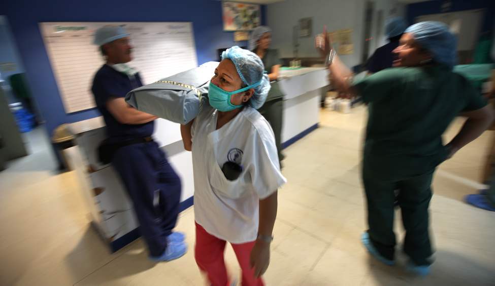 A Nicaraguan OR nurse shoulders wrapped sterile instruments to the OR.
