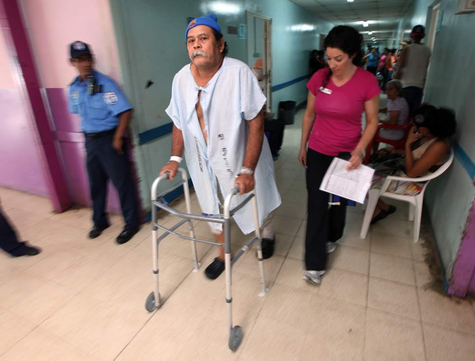 Juan Canda explores the hallway near his recovery ward under the watchful care of staff.