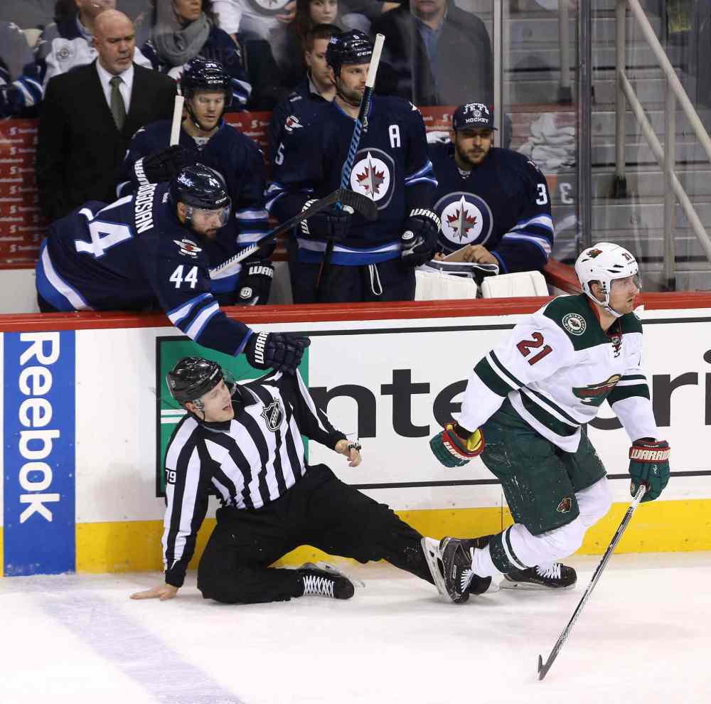 Trevor Hagan / The Canadian Press
Winnipeg Jets' Zach Bogosian (44) assists linesman Kiel Murchison (79) after he was hit by Minnesota Wild Kyle Brodziak (21) and Jets' Adam Lowry (17), not shown, during third period.