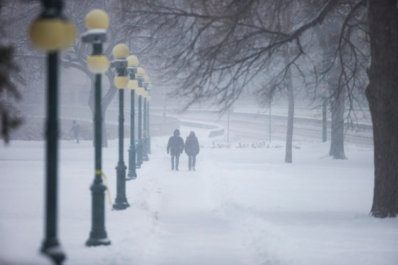 People walk through the snowy Manitoba legislative grounds in Winnipeg on Tuesday. (Mikaela MacKenzie / Winnipeg Free Press)