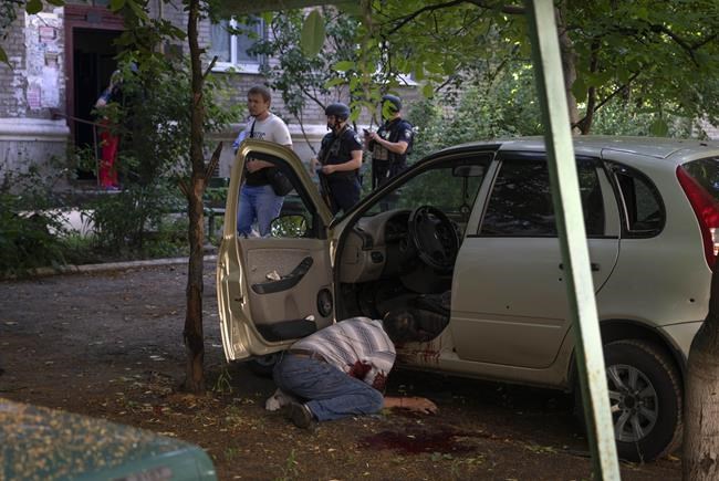 EDS NOTE: GRAPHIC CONTENT - A dead body of a man killed by the Russian shelling lies by his car in city center in Slavyansk, Donetsk region, Ukraine, Monday, June 27, 2022. (AP Photo/Efrem Lukatsky)