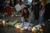 Dozens of mourners gather for a vigil near Central Avenue and St. Johns Avenue in downtown Highland Park, one day after a gunman killed at least seven people and wounded dozens more by firing an AR-15-style rifle from a rooftop onto a crowd attending Highland Park's Fourth of July parade, Tuesday, July 5, 2022 in Highland Park, Ill.. (Ashlee Rezin/Chicago Sun-Times via AP)