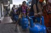 A boy tries to lift an empty cylinder as he along with others wait in a queue to buy domestic gas at a distribution center, in Colombo, Sri Lanka, Tuesday, July 12, 2022. A political vacuum continues in Sri Lanka with opposition leaders yet to agree on who should replace its roundly rejected leaders, whose residences are occupied by protesters angry over the country’s deep economic woes. (AP Photo/Rafiq Maqbool)