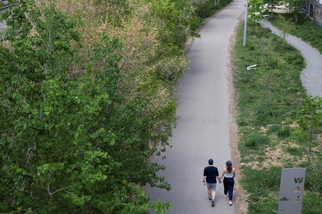 A couple holds hands as they walk along the West Toronto Railpath during Sunday, May 23, 2021. A new tranche of census data shows Canadians are increasingly likely to live in common-law partnerships rather than officially tying the knot. THE CANADIAN PRESS/Tijana Martin