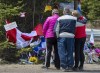 A family pays their respects to victims of the mass killings at a checkpoint on Portapique Road in Portapique, N.S. on Friday, April 24, 2020. THE CANADIAN PRESS/Andrew Vaughan