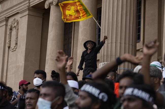 A protester waves a national flag and shouts slogans demanding elected president Ranil Wickremesinghe step down during a protest at the presidential secretariat premise in Colombo, Sri Lanka, Wednesday, July 20, 2022. Sri Lanka's prime minister was elected president Wednesday by lawmakers who opted for a seasoned, veteran leader to lead the country out of economic collapse, despite widespread public opposition.(AP Photo/Rafiq Maqbool)