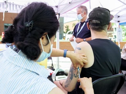 Brian Maci, from New York, receives a monkeypox vaccine at an outdoor walk-in clinic in Montreal, Saturday, July 23, 2022. Tourists are among those lining up to get monkeypox vaccines in Montreal, as the World Health Organization declares the virus a global health emergency. THE CANADIAN PRESS/Graham Hughes