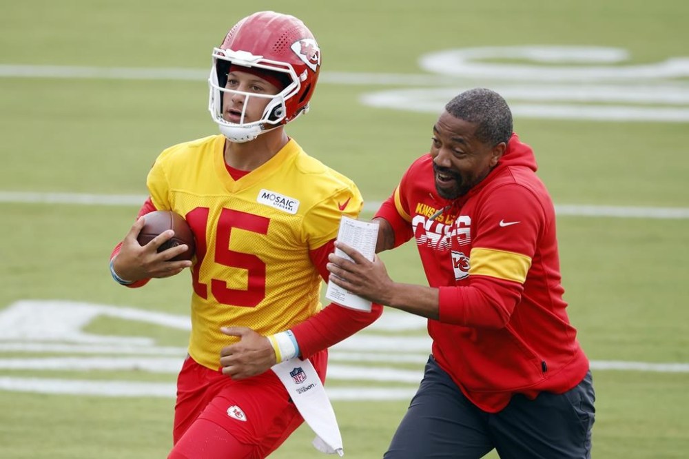 Kansas City Chiefs quarterback Patrick Mahomes (15) completes a running play as running backs coach Greg Lewis pursues during an NFL football training camp at Missouri Western State University in St. Joseph, Mo., Sunday, July 24, 2022. (AP Photo/Colin E. Braley)