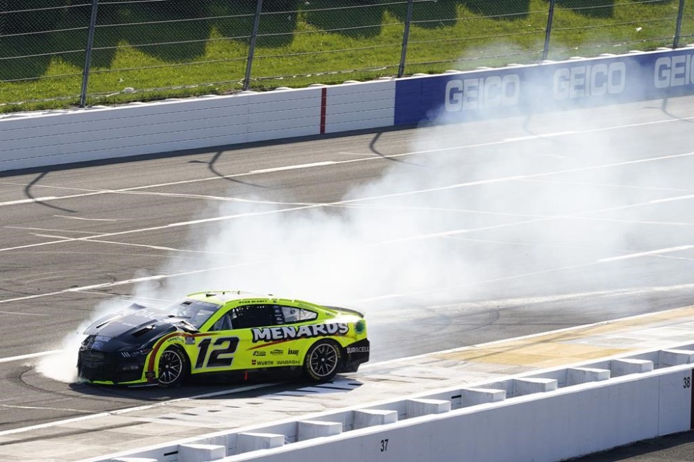 Smoke surrounds the car of Ryan Blaney (12) after an incident during a NASCAR Cup Series auto race at Pocono Raceway, Sunday, July 24, 2022, in Long Pond, Pa. (AP Photo/Matt Slocum)