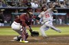 Washington Nationals' Yadiel Hernandez (29) scores against Arizona Diamondbacks catcher Jose Herrera, left, after a throwing error by third baseman Josh Rojas in the sixth inning during a baseball game, Sunday, July 24, 2022, in Phoenix. (AP Photo/Rick Scuteri)