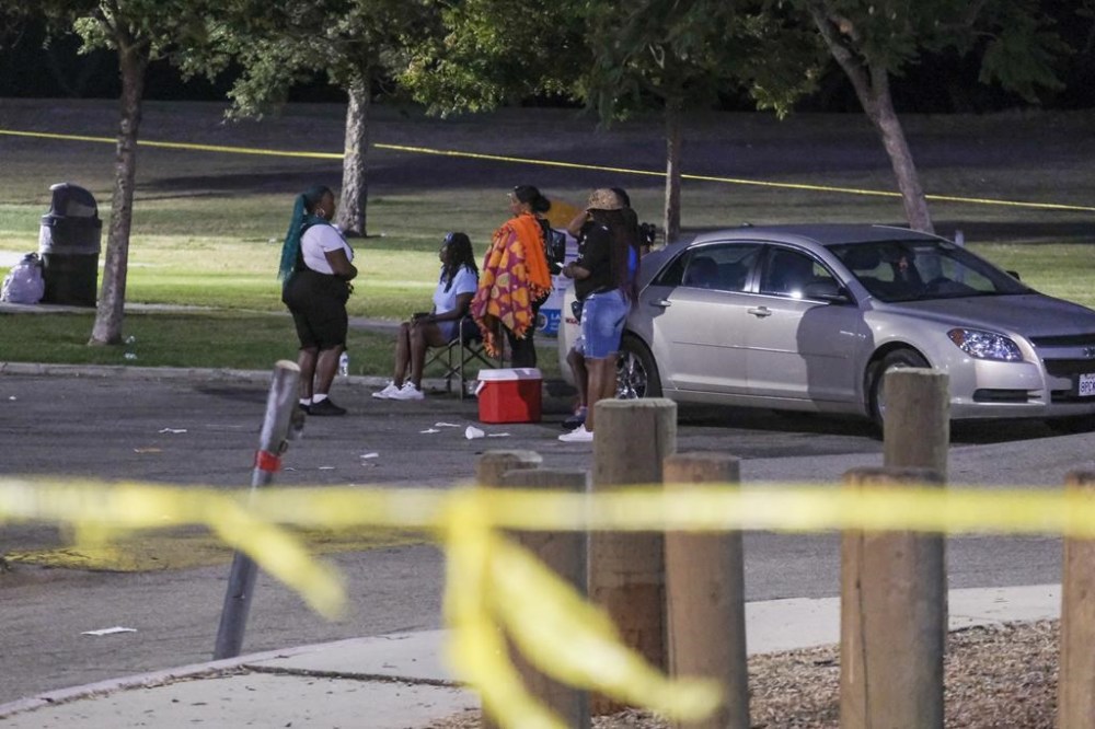 People wait at a parking lot near the scene of a shooting at Peck Park in San Pedro, Calif., Sunday, July 24, 2022. (AP Photo/Ringo H.W. Chiu)
