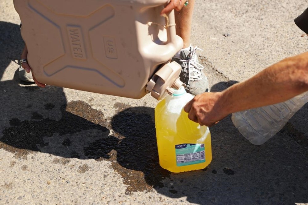 Maggy Johnston, ARCHES outreach coordinator, fills water bottles with Gatorade for houseless individuals during a heat wave in Salem, Ore., on Tuesday, July 26, 2022. Oregon Gov. Kate Brown declared a state of emergency across much of the state, warning the extreme temperatures may cause utility outages and transportation disruptions. (Brian Hayes/Statesman-Journal via AP)