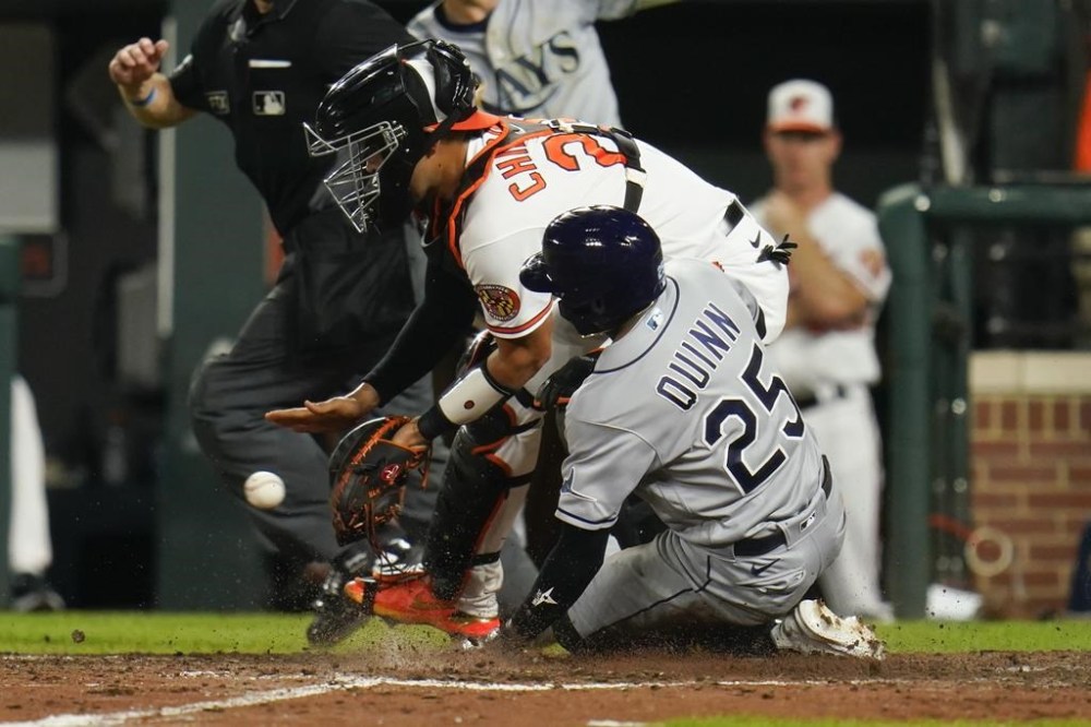 Tampa Bay Rays' Roman Quinn (25) scores a run as Baltimore Orioles catcher Robinson Chirinos waits for the throw on a two-run bases loaded double by Randy Arozarena during the 10th inning of a baseball game, Wednesday, July 27, 2022, in Baltimore. The Rays won 6-4 in ten innings. Rays' Taylor Walls also scored on the play. (AP Photo/Julio Cortez)