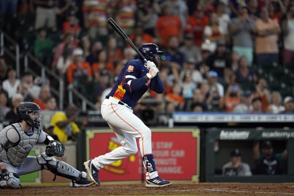 Houston Astros' Yordan Alvarez, right, hits a game-winning RBI-single during the 10th inning of a baseball game as Seattle Mariners catcher Cal Raleigh watches Sunday, July 31, 2022, in Houston. The Astros won 3-2 in 10 innings. (AP Photo/David J. Phillip)
