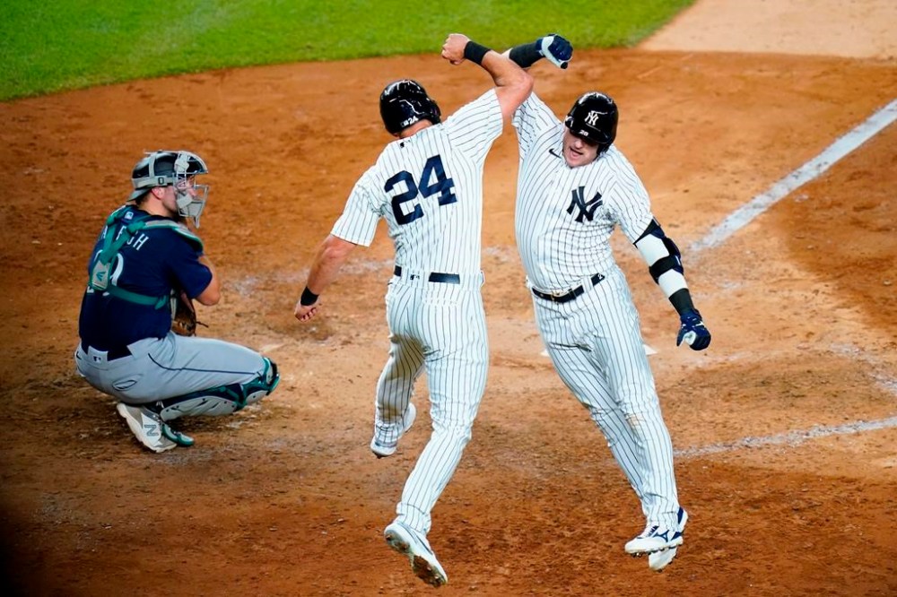 Seattle Mariners catcher Cal Raleigh watches as New York Yankees' Matt Carpenter, center, celebrates with teammate Josh Donaldson after Donaldson hit a two-run home run during the sixth inning of a baseball game Tuesday, Aug. 2, 2022, in New York. (AP Photo/Frank Franklin II)