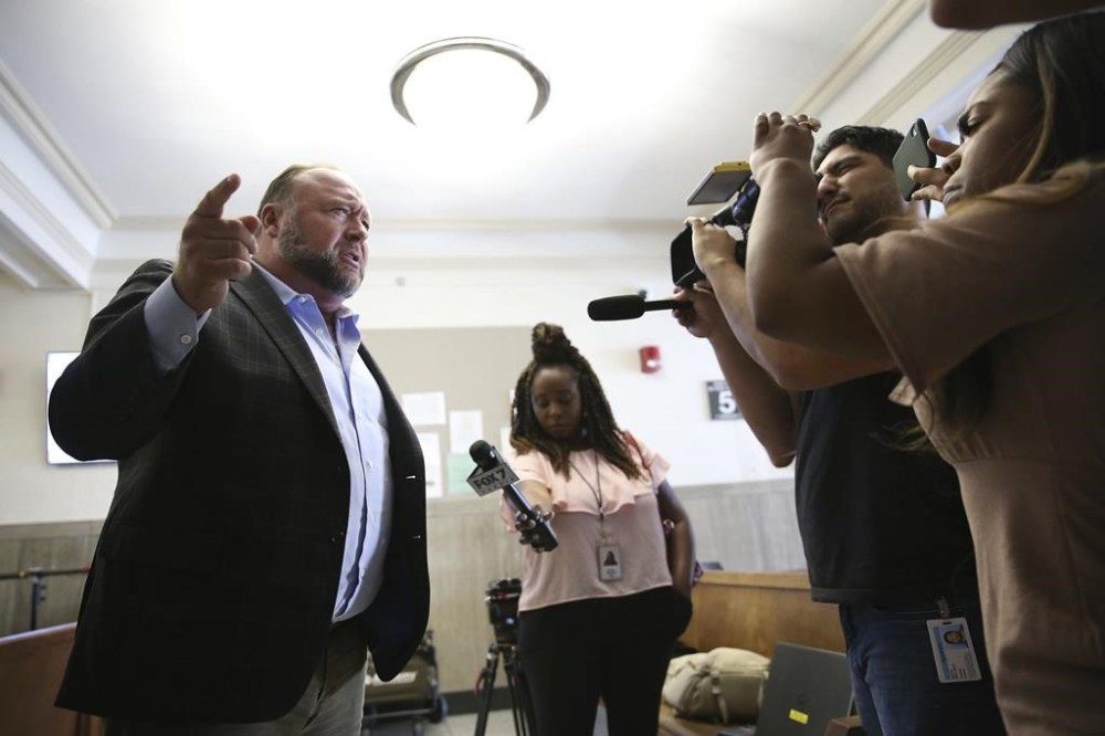 Alex Jones talks to media during a midday break during the trial at the Travis County Courthouse in Austin, Texas, Tuesday, July 26, 2022. An attorney for the parents of one of the children who were killed in the Sandy Hook Elementary School shooting told jurors that Jones repeatedly “lied and attacked the parents of murdered children” when he told his Infowars audience that the 2012 attack was a hoax. Attorney Mark Bankston said during his opening statement to determine damages against Jones that Jones created a “massive campaign of lies” and recruited “wild extremists from the fringes of the internet ... who were as cruel as Mr. Jones wanted them to be
