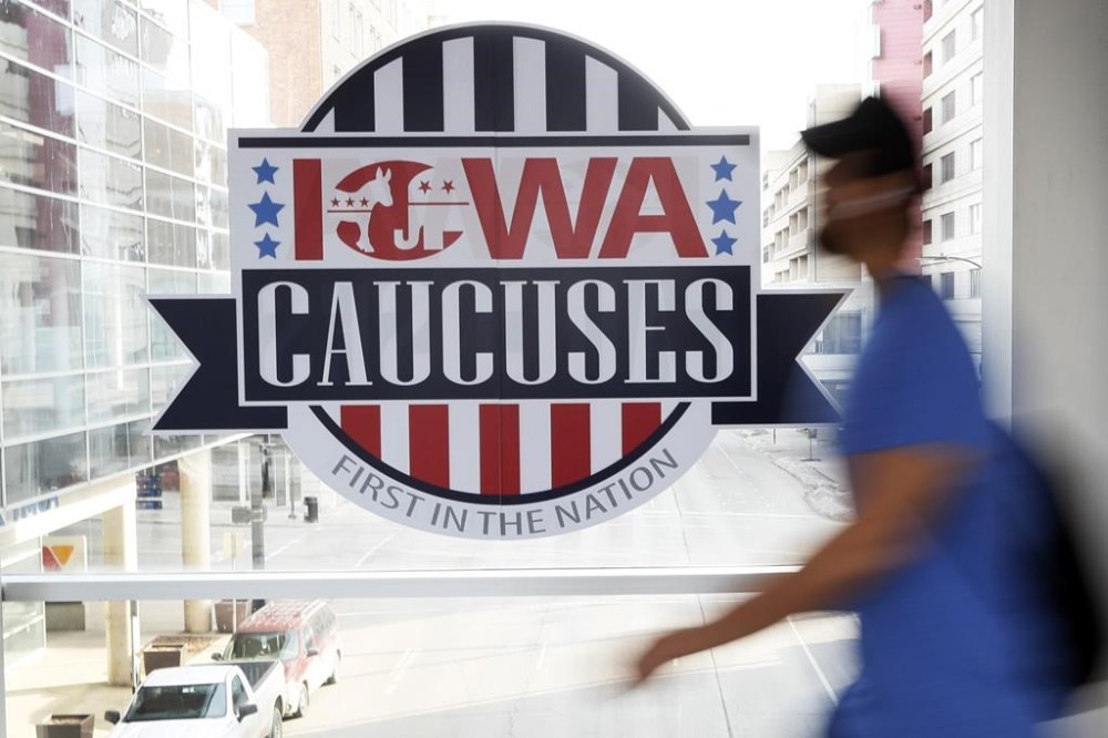 FILE - A pedestrian walks past a sign for the Iowa Caucuses on a downtown skywalk, in Des Moines, Iowa, on Feb. 4, 2020. Democrats may be moving toward shaking up their presidential nominating process starting in 2024. They're poised to boot Iowa from the lead-off spot as part of a broader effort to allow to go earlier less overwhelmingly white states that better reflect the party's diverse electorate. (AP Photo/Charlie Neibergall, File)