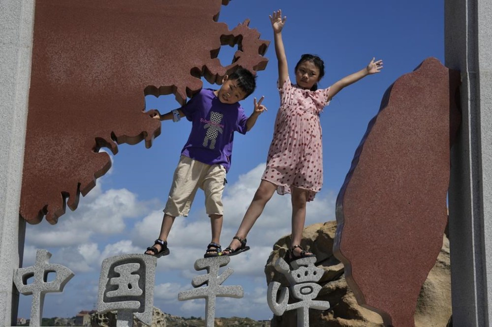 Children pose for photos at the 68-nautical-mile scenic spot, the closest point in mainland China to the island of Taiwan, in Pingtan in southeastern China's Fujian Province, Friday, Aug. 5, 2022. China conducted