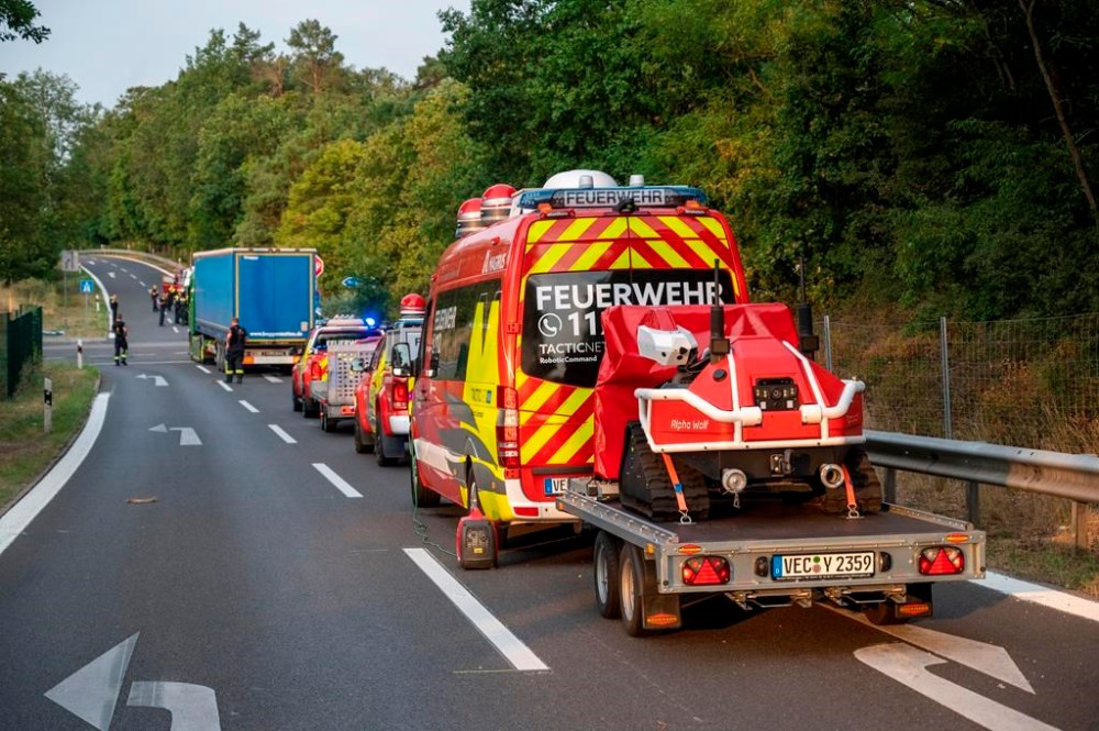 Firefighting robots from the Vechta fire department stand near the scene of a fire in the Grunewald forest in Berlin, Germany, Friday, Aug.5, 2022. A fire accompanied by explosions at a police ammunition dump in a Berlin forest was contained and parts of it were extinguished on Friday, but authorities were still waiting to get access to the dump itself. (Christophe Gateau/dpa via AP)