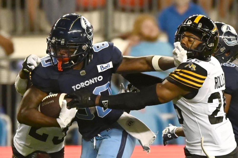 Toronto Argonauts wide receiver DaVaris Daniels (80) is tackled by Hamilton Tiger-Cats defensive back Jumal Rolle (25) during second half CFL football action in Toronto on Saturday, August 6, 2022. THE CANADIAN PRESS/Jon Blacker