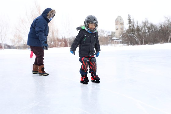Asher Bataller, 4, with his dad close by, takes baby steps along the ice at the Duck Pond in Assiniboine Park. (Ruth Bonneville / Winnipeg Free Press)