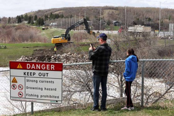 Workers add rocks to the eroding shoreline of the Little Saskatchewan River at the Minnedosa dam on Tuesday. (Tim Smith / Brandon Sun)